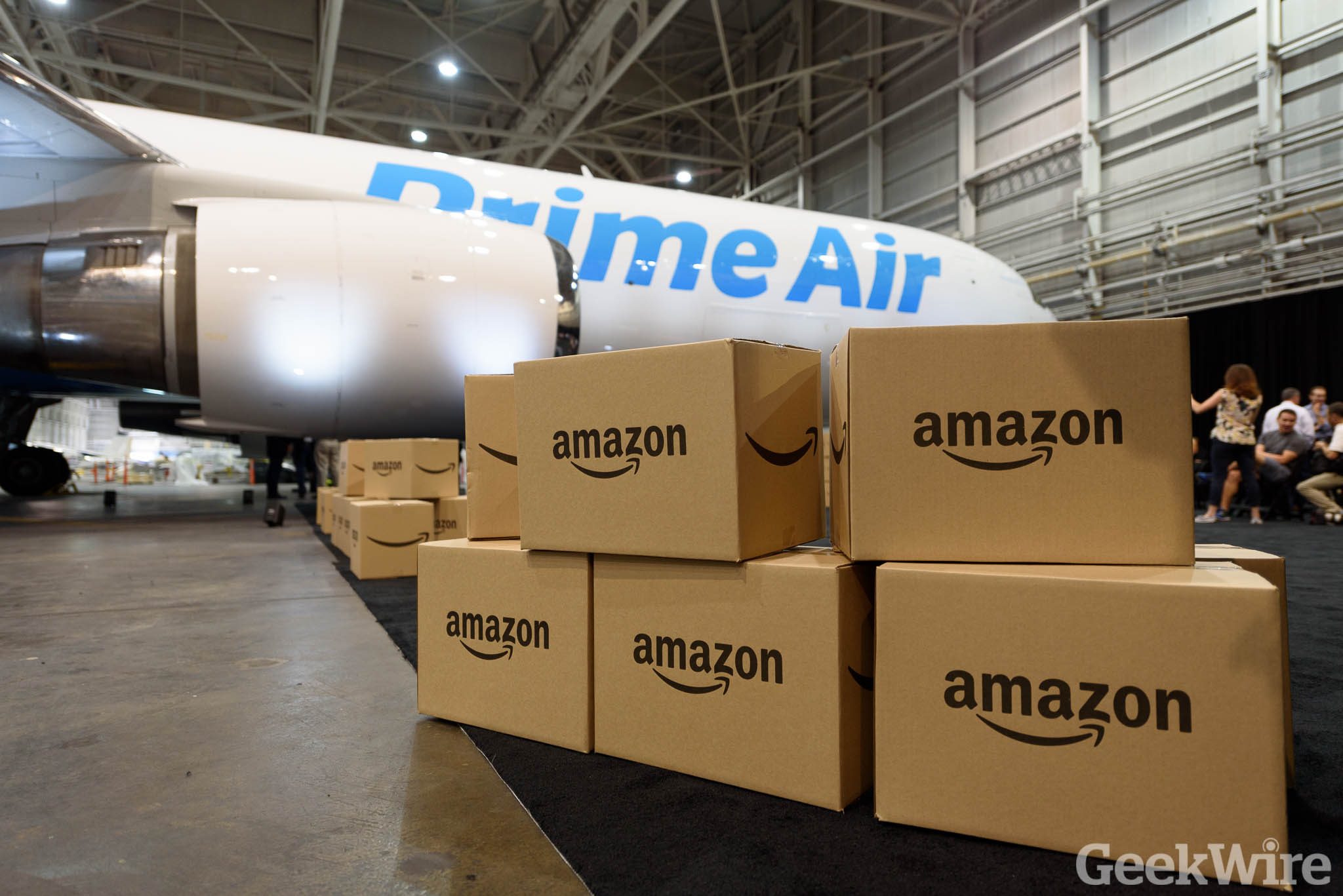 Et fraktfly fra Amazon med Prime-logoen på siden. I forgrunnen pakker fra Amazon klare til levering.